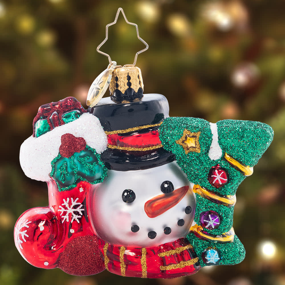 Red faceted Christmas ornament with a smiling snowman face peeking from the top.