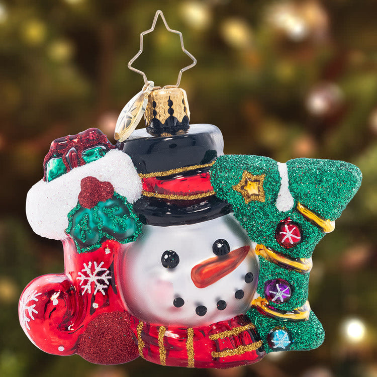 Red faceted Christmas ornament with a smiling snowman face peeking from the top.