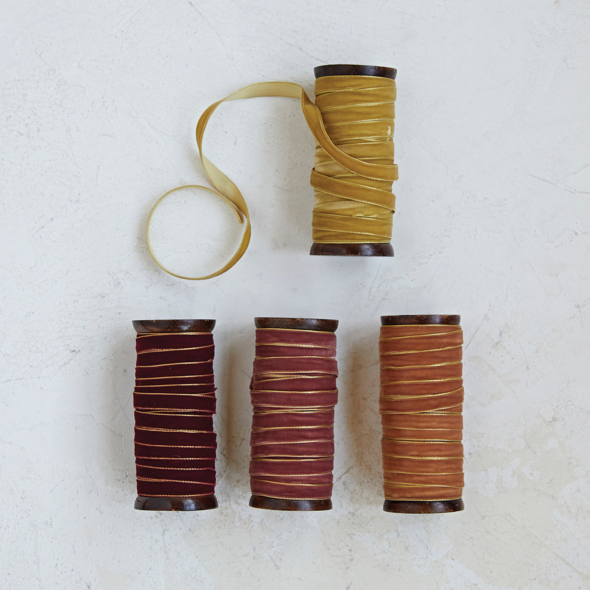 Four wood spools of 10-yard velvet ribbon with metallic edges in gold, burgundy, mauve, and copper.