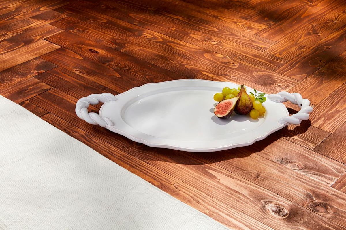 White terracotta Twisted Handle Platter with fresh figs and grapes on a wooden floor.