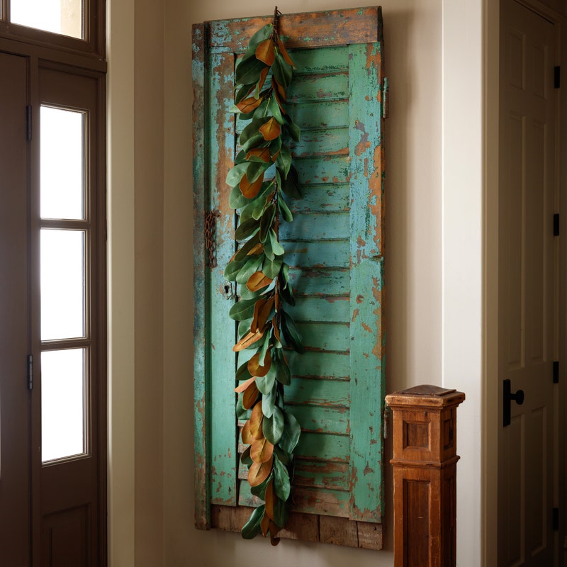 Abbey Magnolia 72-inch garland with deep green and brown leaves draped over a rustic teal shutter.
