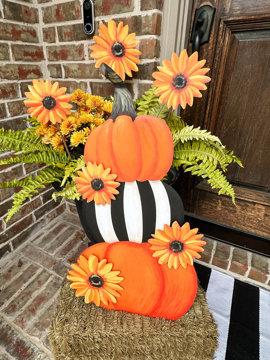 Metal sunflower garden stake with orange petals and a dark center, shown in a fall display.