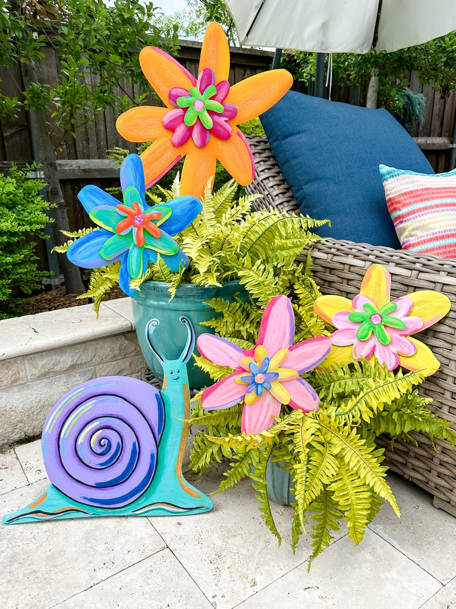 Colorful wooden snail and flower garden stakes in purple, teal, orange, blue, pink, and yellow.