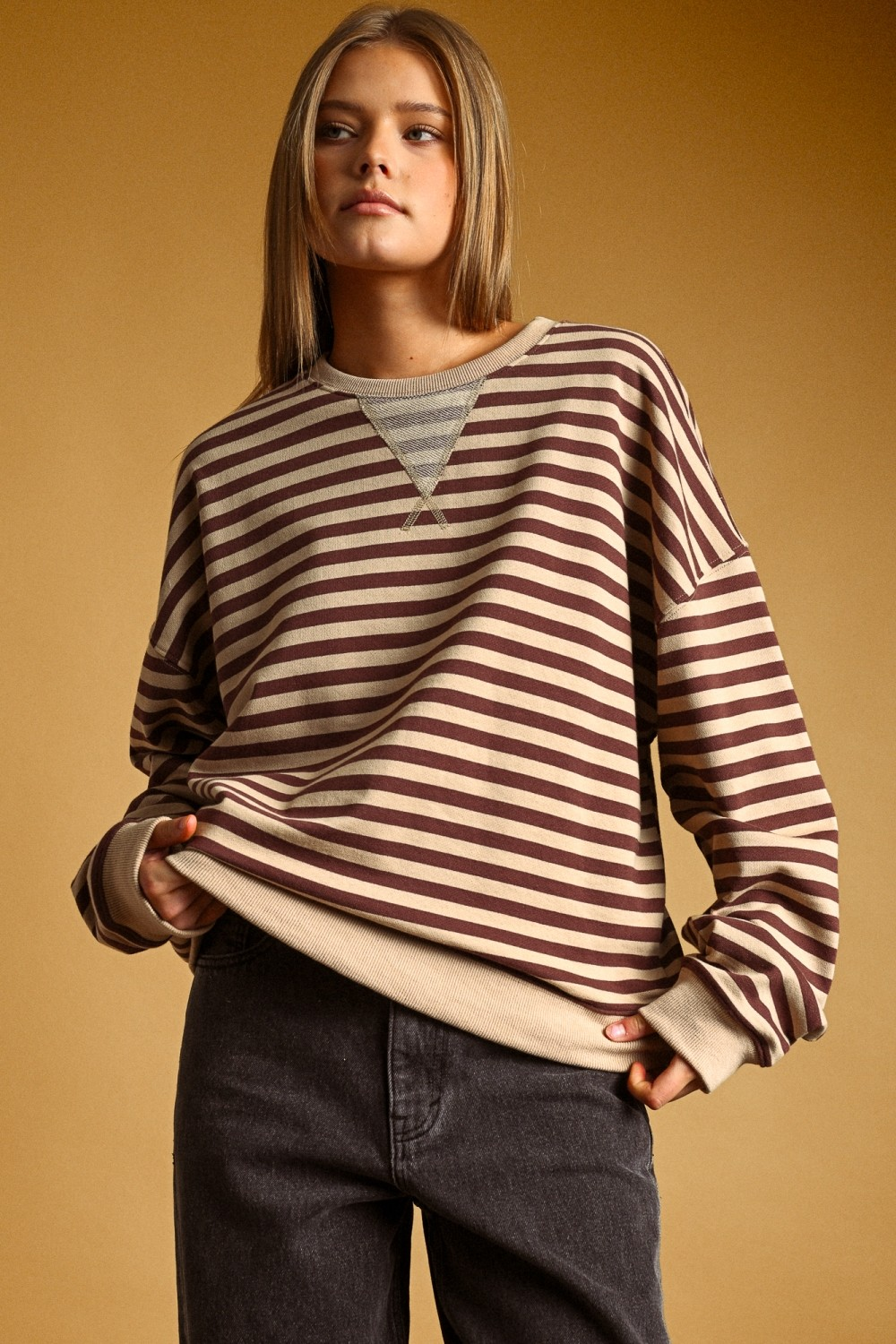Woman wearing the Evie Striped Knitted Long Sleeve Pullover in brown and tan with a V-stitch neck.