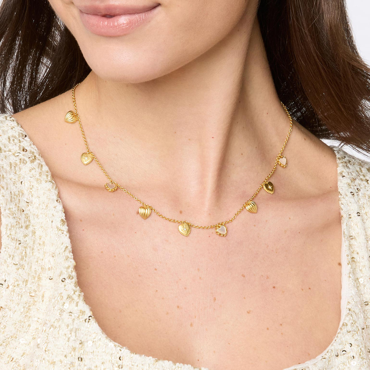 Woman wearing a gold Heart Delicate Charm Necklace with mother of pearl and CZ accents.