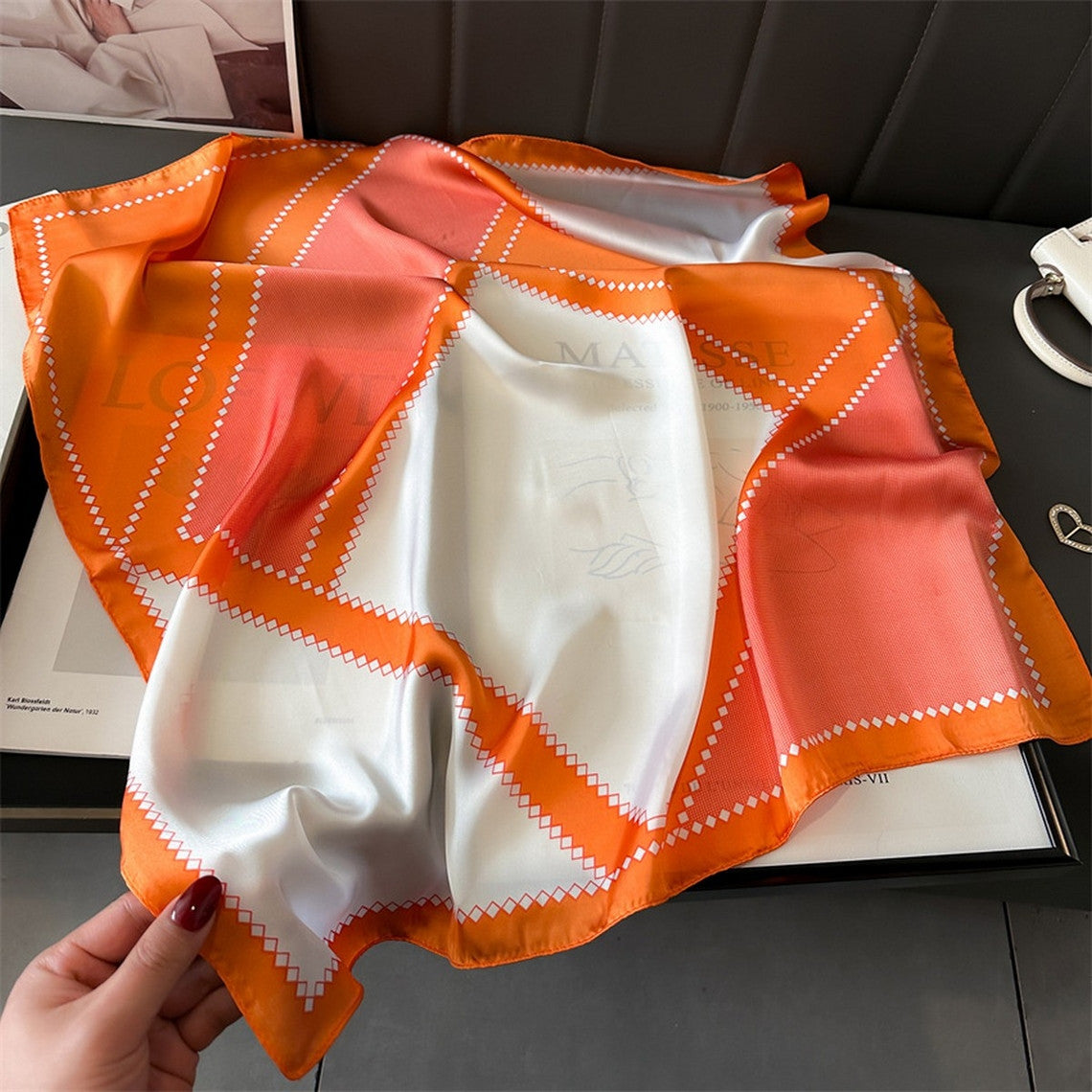 70cm geometric print scarf in orange, pink, and white with a diamond pattern border.