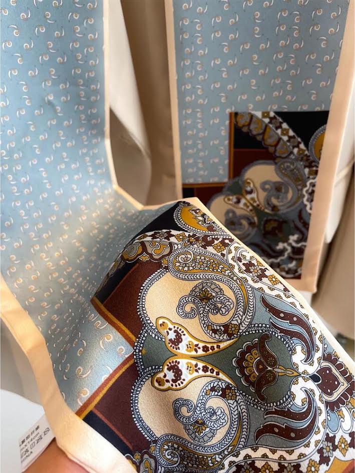 Reversible silk scarf featuring a blue patterned side and a brown and gold paisley design.