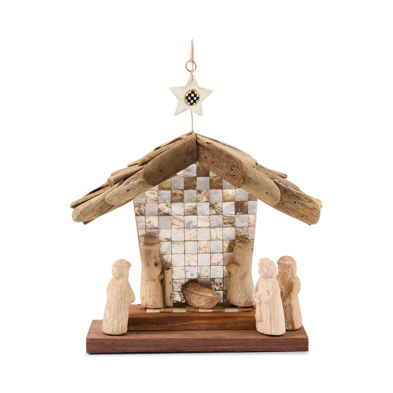 Natural Noel Nativity scene made of driftwood and carved stone figures with a checkered backdrop.