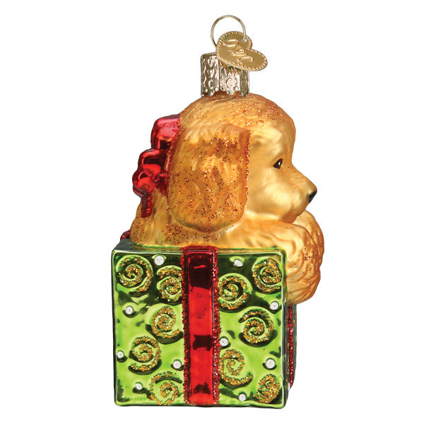 Doodle puppy glass ornament sitting inside a green gift box with a red ribbon and glitter accents.