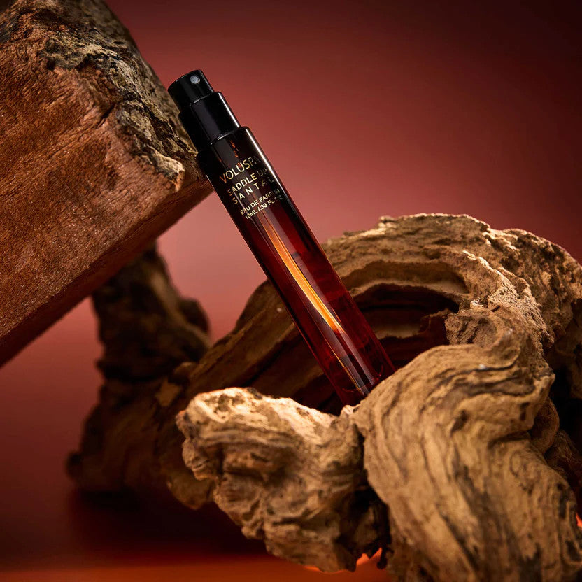 Voluspa Saddle Up Santal 10ml Eau De Parfum travel spray bottle nestled in rustic driftwood.