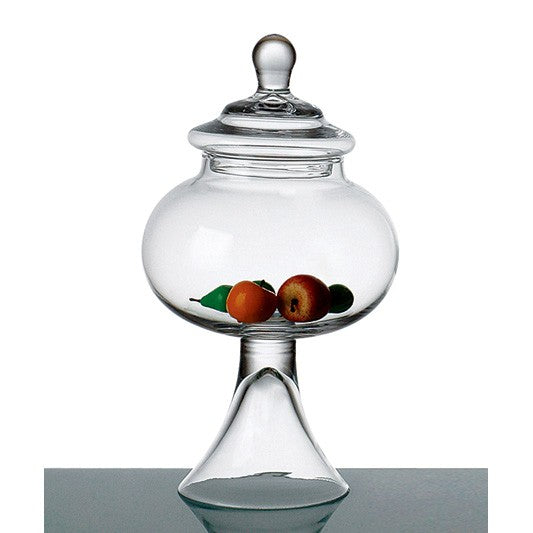 Clear glass apothecary jar with lid and pedestal base, containing small decorative fruit.