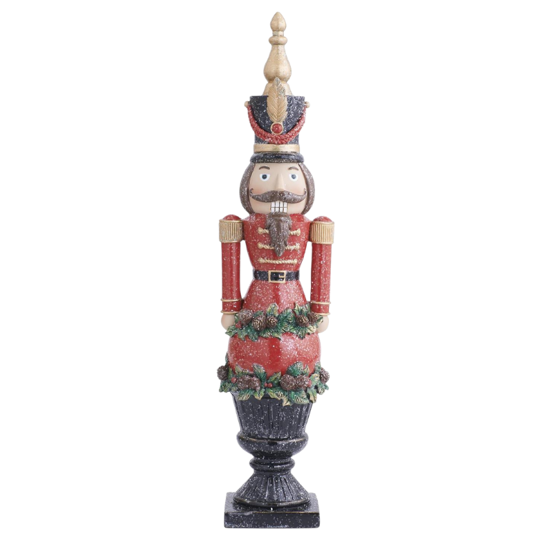 Resin glittered nutcracker in a red uniform standing on a black pedestal with pinecone accents.