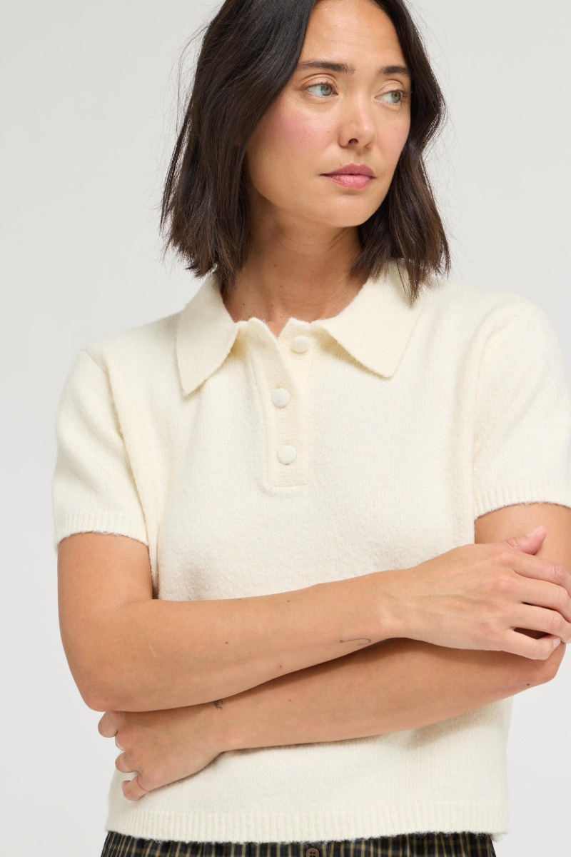 Woman wearing the Marian ivory short sleeve knit top with a classic collar and buttoned placket.