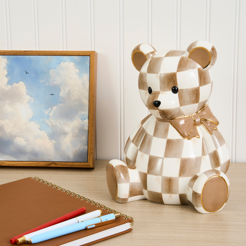 Mocha Bear Bank with a brown and white checkered pattern and a gold-trimmed bow on a desk.