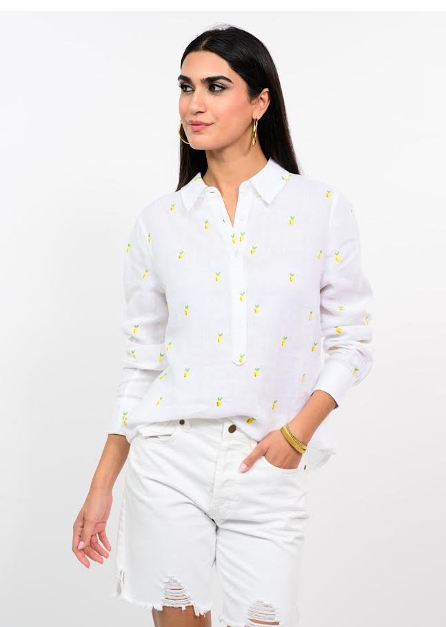 Woman wearing a white long-sleeve Amie Linen Lemon Shirt with embroidered yellow lemon patterns.