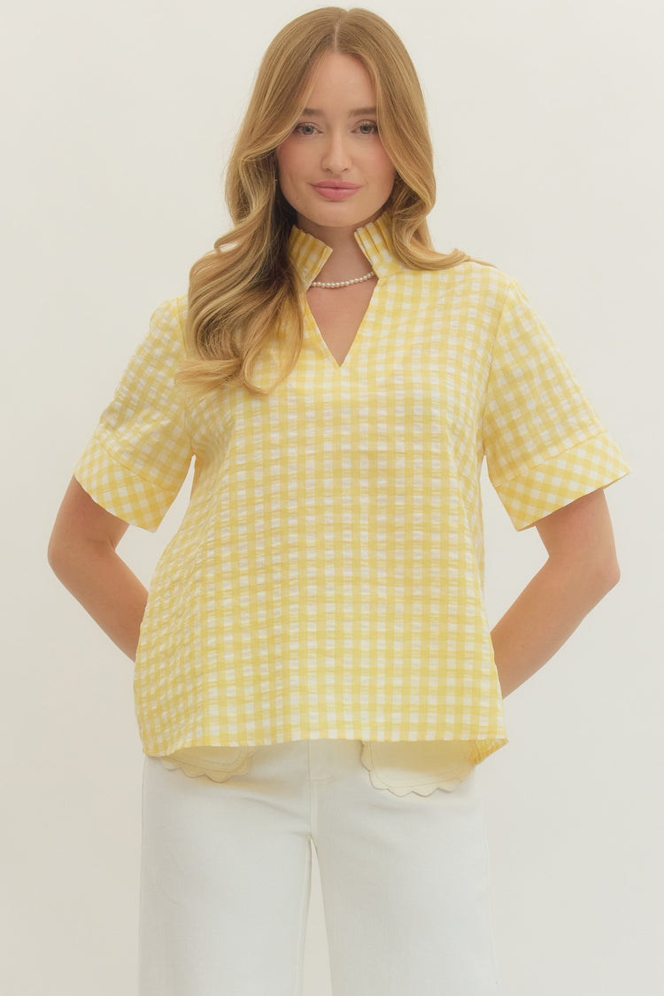 Woman wearing a Natalie Gingham Short Sleeve Top in yellow and white with a stand collar V-neck.