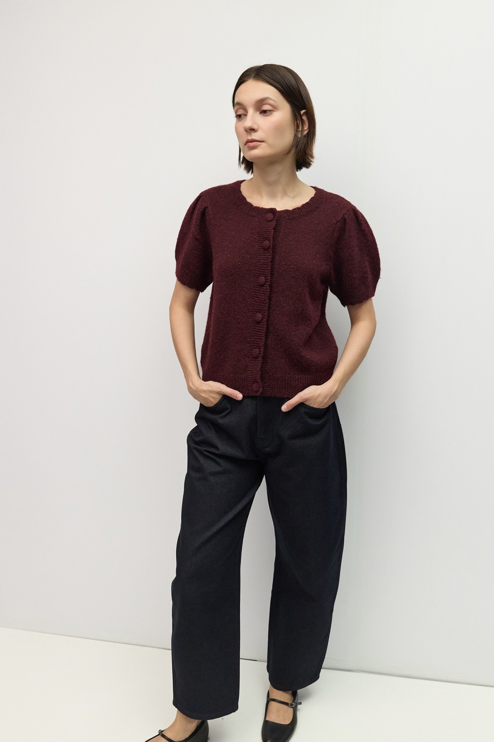Woman wearing the Mary Kate Top in burgundy with short puff sleeves and dark wide-leg trousers.
