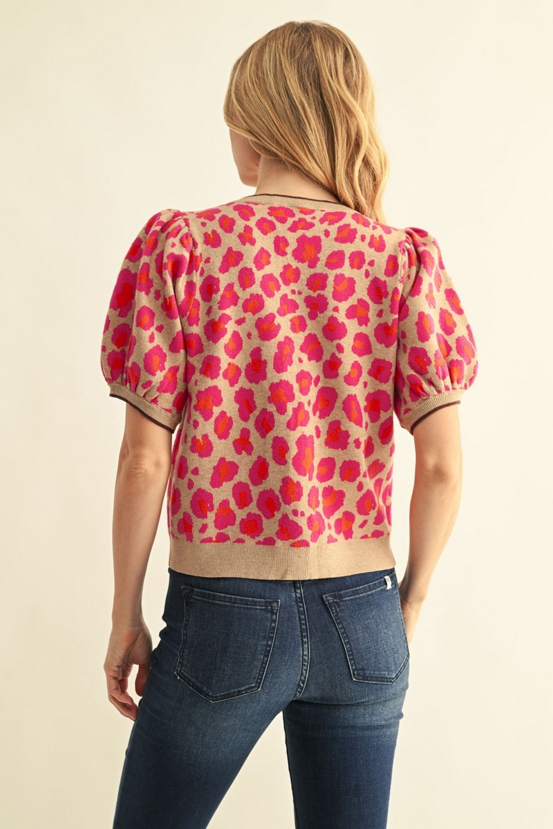 Back view of a woman wearing a short puff-sleeve leopard print sweater cardigan in pink and tan.