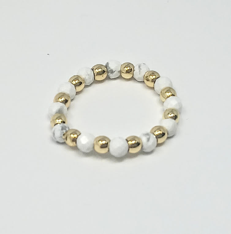 A beaded ring featuring alternating white marble stones and small gold-tone metallic spheres.