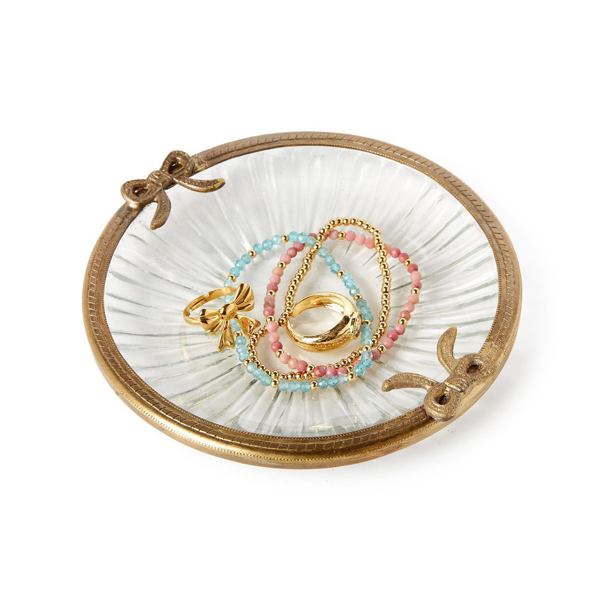 Antique gold finish round glass trinket tray with bow accents holding jewelry.