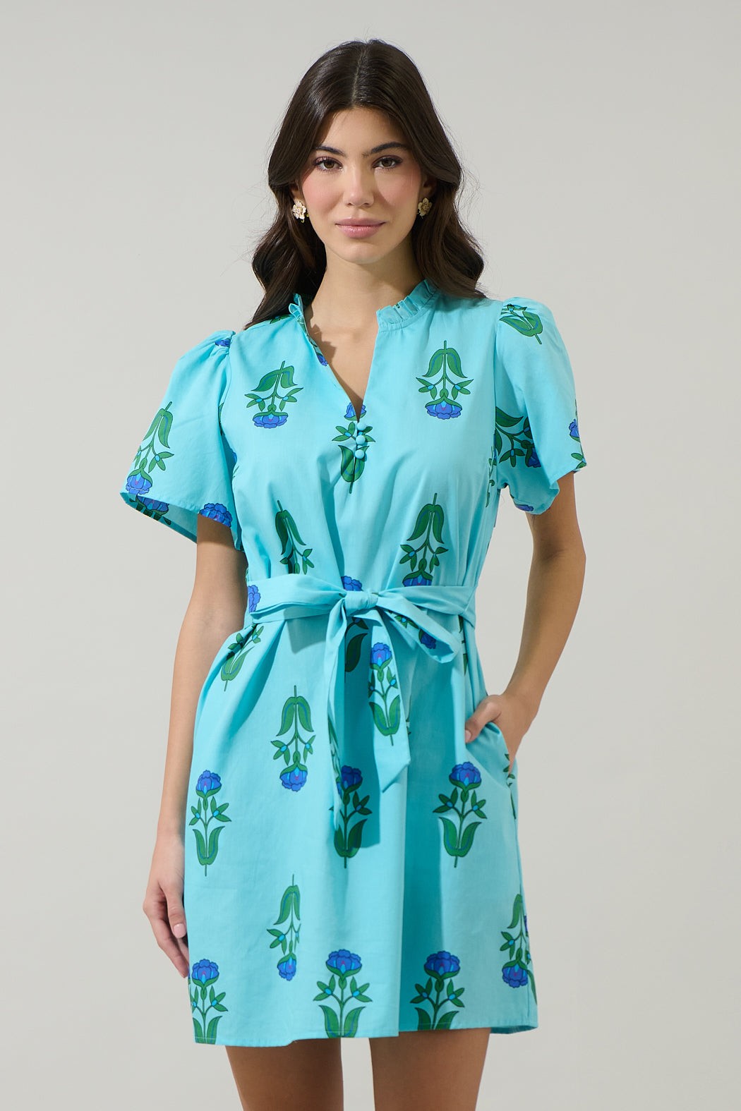 Woman wearing the Amena Floral Ema Shift Mini Dress in light blue with green and blue floral print.