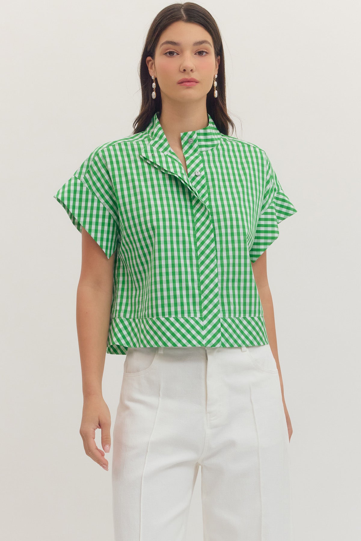 Woman wearing a green and white Noemi gingham print cap sleeve top with a stand collar.