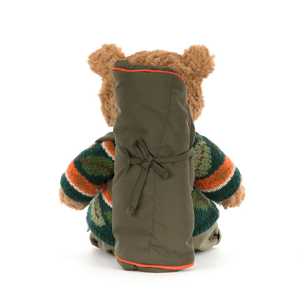 Rear view of Bartholomew Bear in a green and orange knit sweater with a rolled-up green sleeping bag.