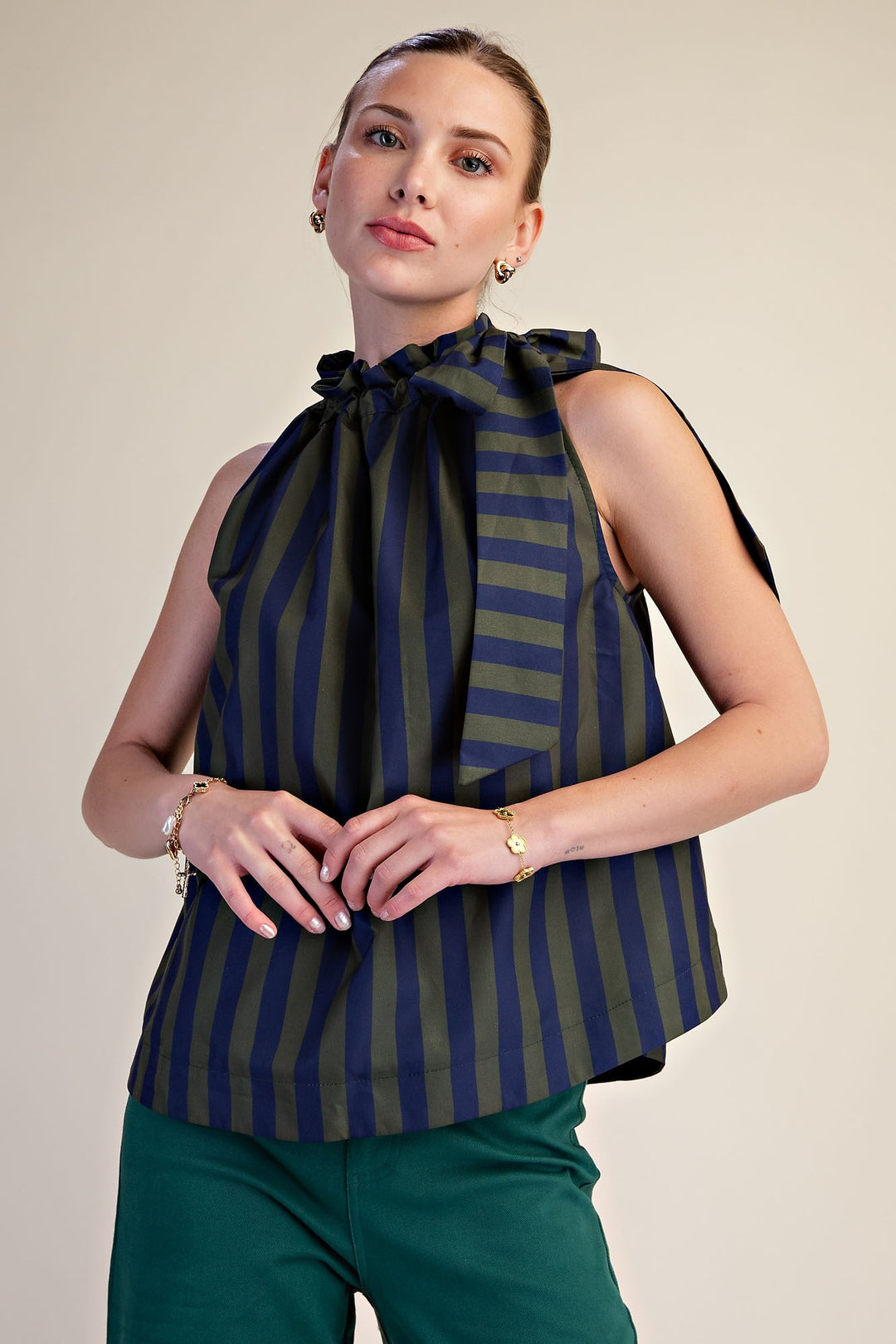 Woman wearing a Jenny Ruffle Neck Tie Sleeveless Stripe Top in navy and olive green.