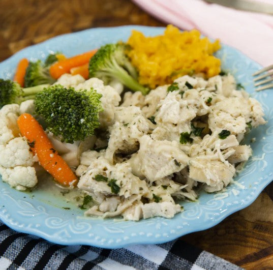 A plate of garlic mozzarella chicken served with steamed broccoli, carrots, and cauliflower.