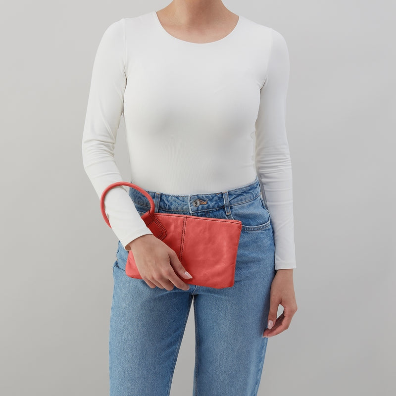 Pink Mirage Sable wristlet with antique brass hardware, zip closure, leather strap, and interior card slots.