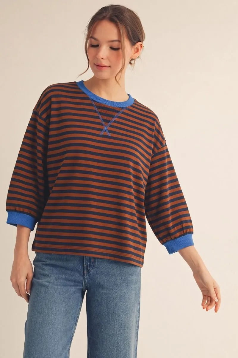 Woman wearing a brown and navy striped casual top with blue V-notched neckline and 3/4 sleeves.