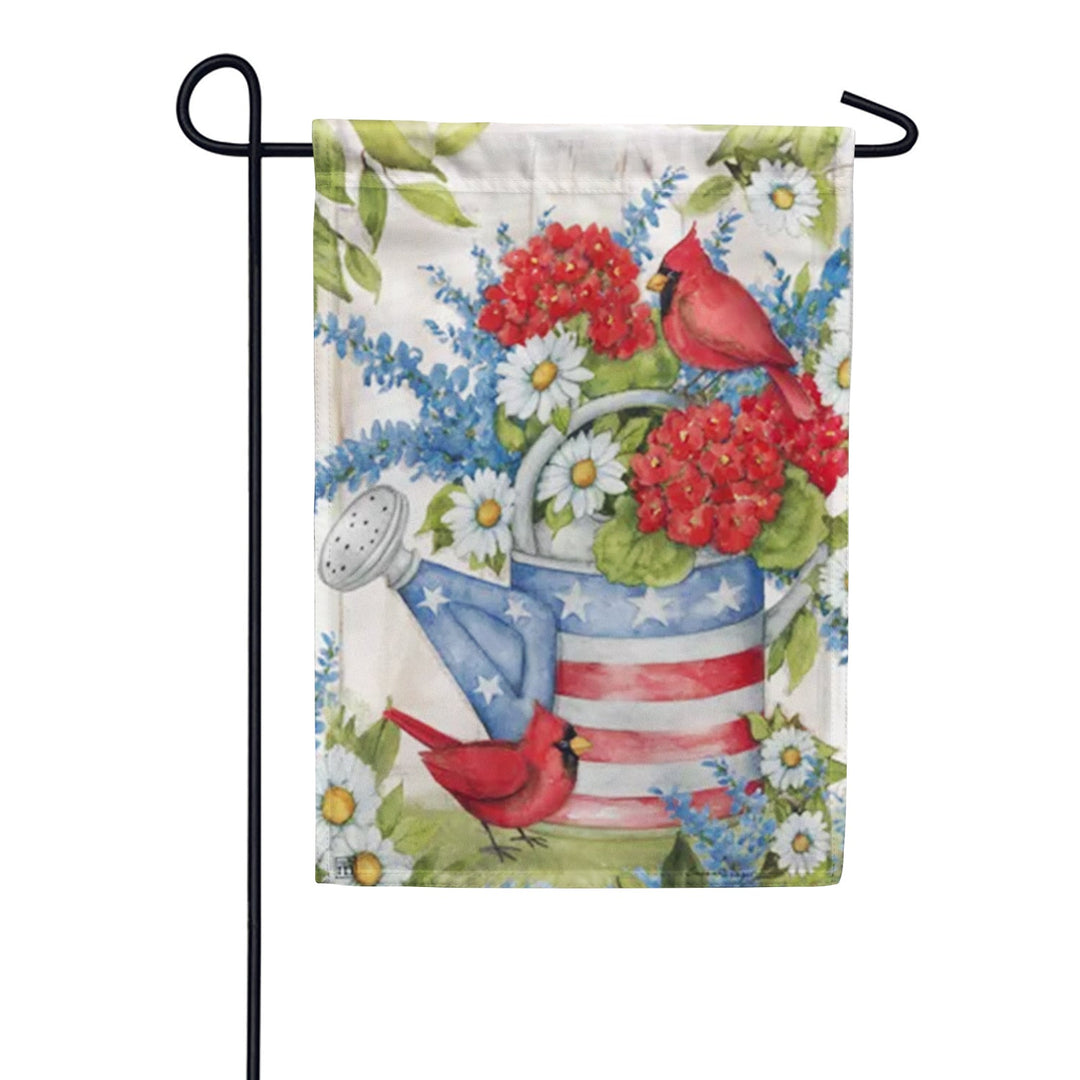 Garden flag with a watering can decorated with American flag pattern, red cardinals, and white and blue flowers.