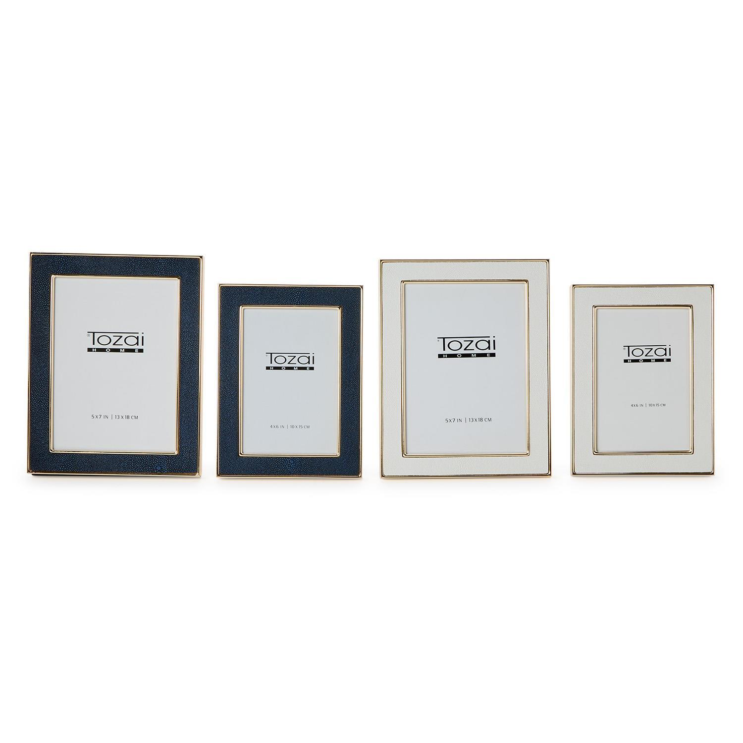 Four Astor Shagreen photo frames in navy blue and cream with gold trim, in two different sizes.