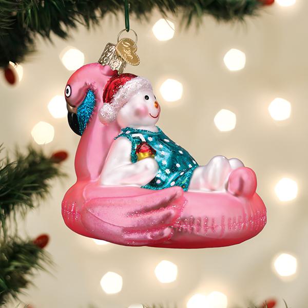 Glass snowman ornament wearing a Santa hat and swimsuit, lounging in a pink flamingo pool float.