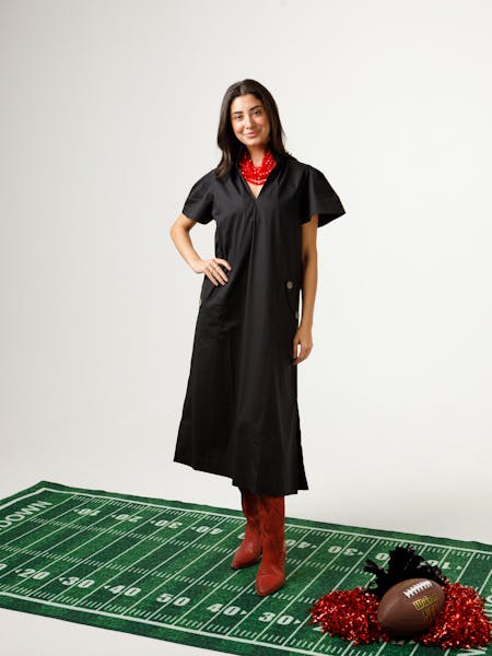 Woman wearing a black Gretchen Dress with a stand collar, pleated sleeves, and red boots.
