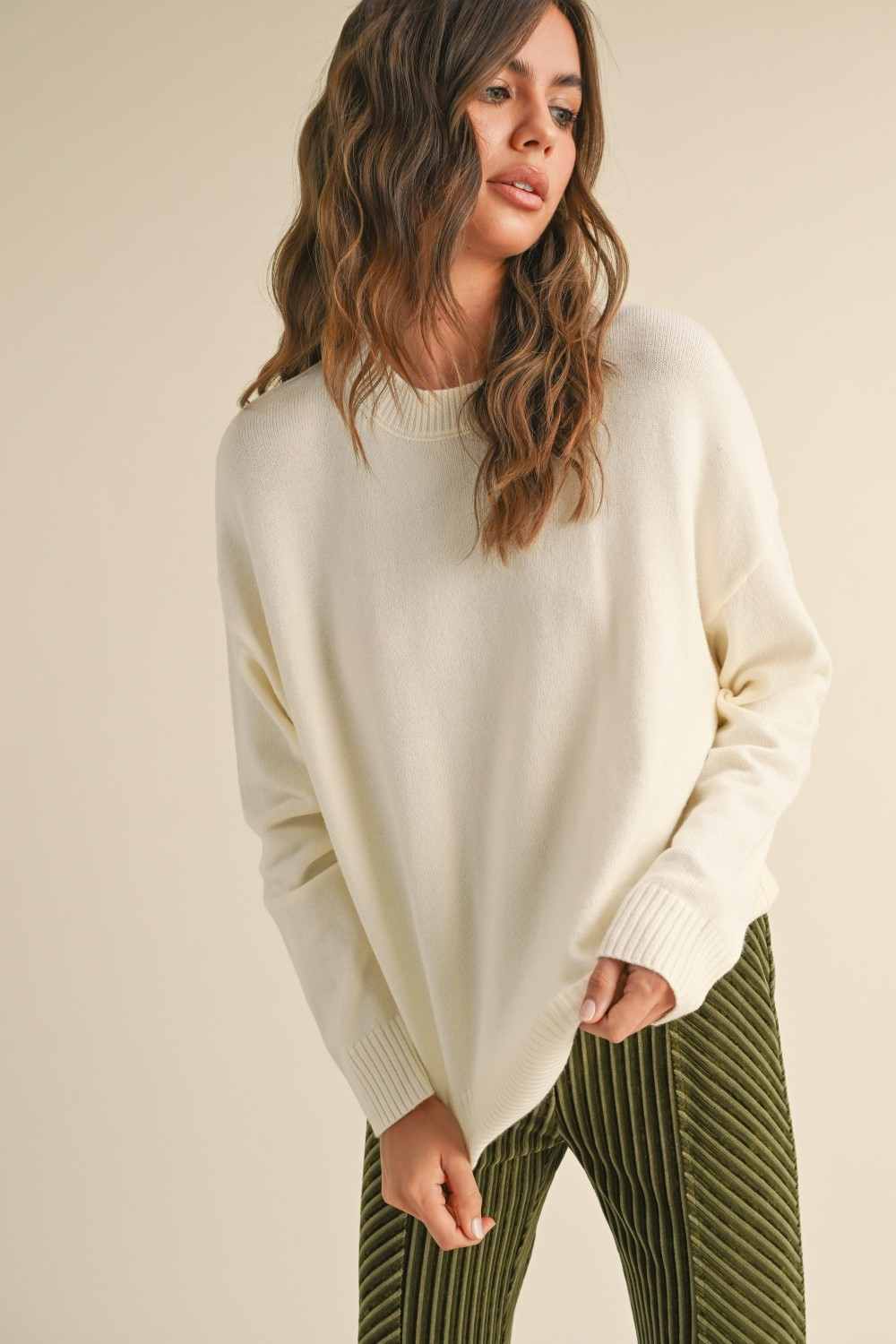 Woman wearing the Ailsa cream-colored relaxed fit sweater with ribbed crew neck and cuffs.