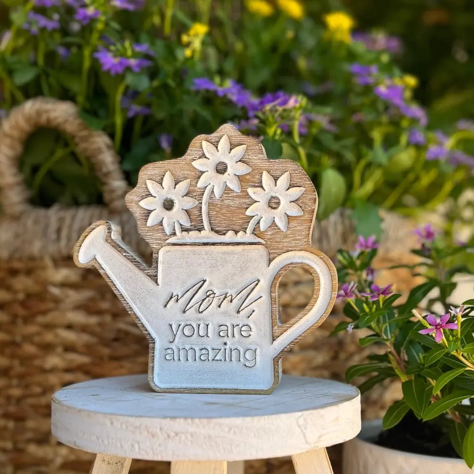 Carved ceramic watering can with rustic floral patterns in earthy tones