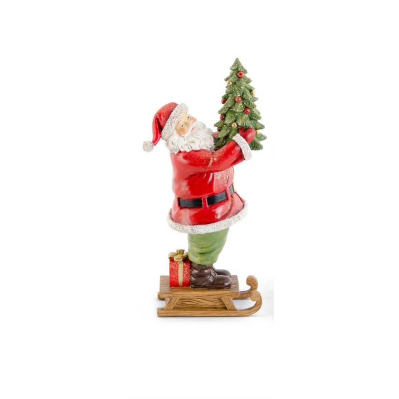 Glittered resin Santa figurine standing on a wooden sled holding a small Christmas tree.