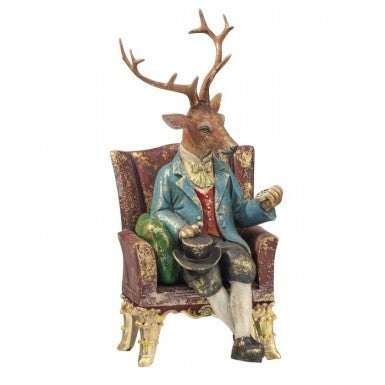 9-inch resin figurine of a gentleman deer with antlers sitting in a red armchair.
