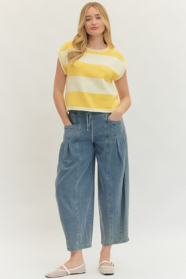 Woman wearing the Kathleen Striped Cap Sleeve Top in yellow and white with wide-leg denim pants.