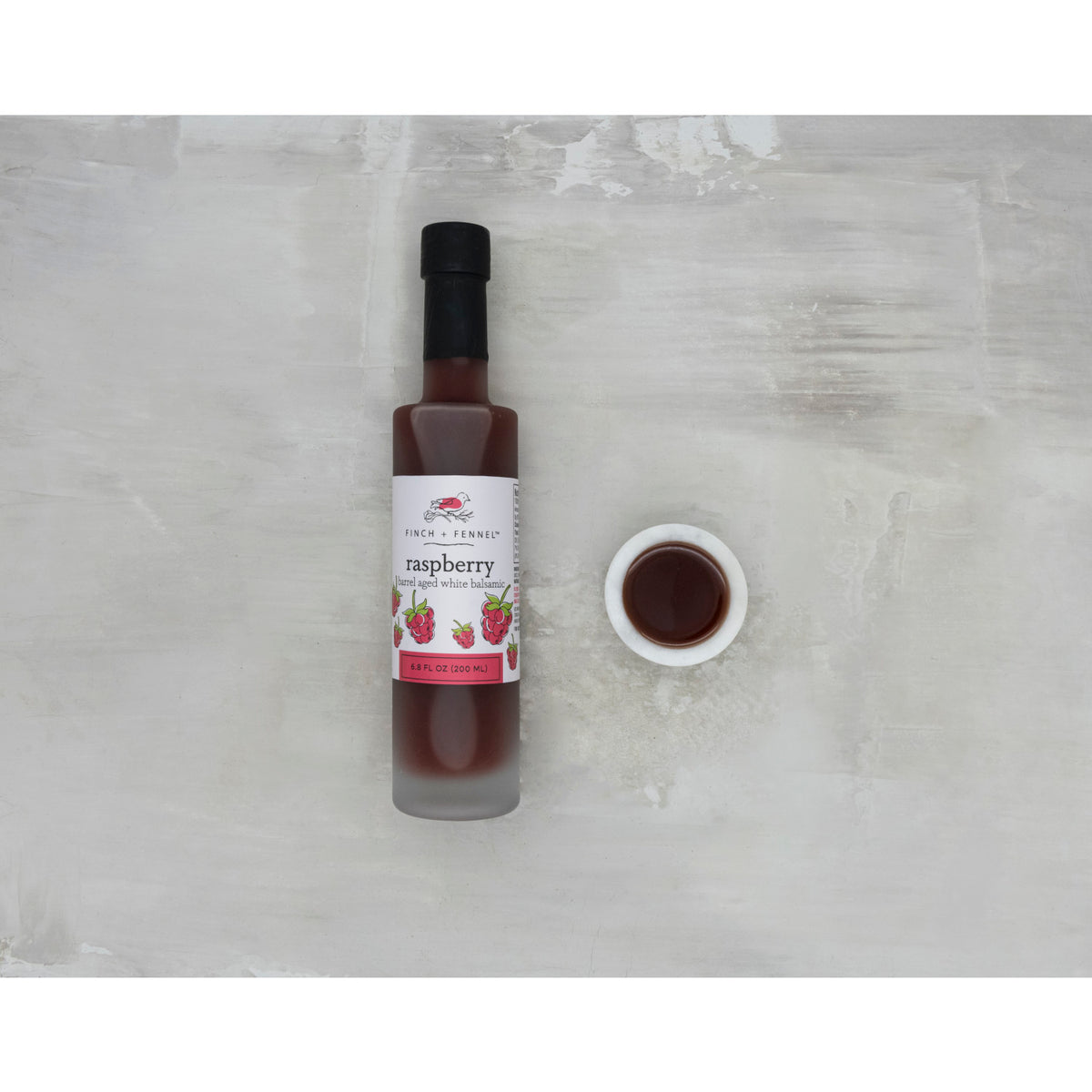 6.8 oz bottle of Raspberry Barrel Aged White Balsamic vinegar with a white label.