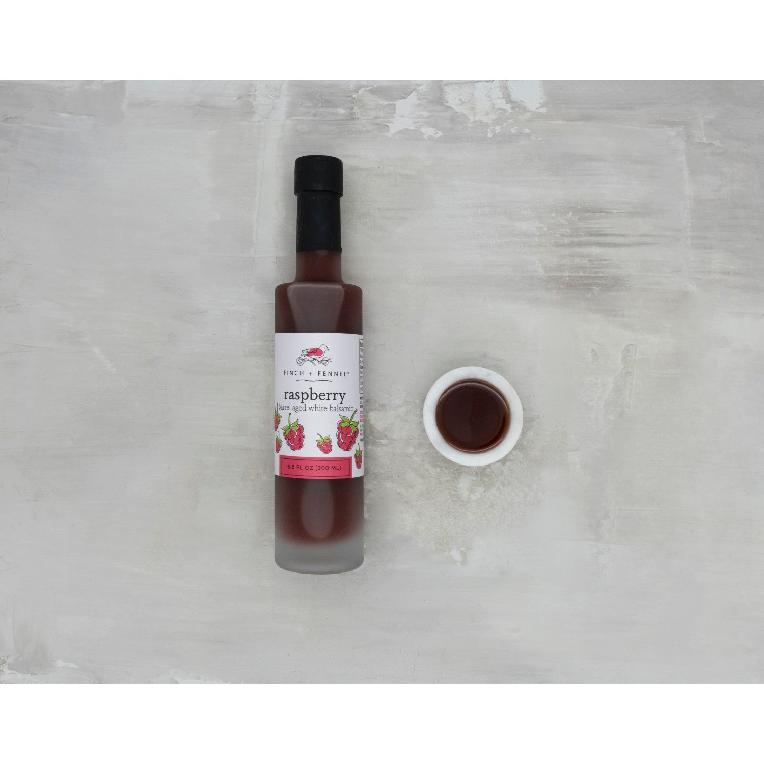 6.8 oz bottle of Raspberry Barrel Aged White Balsamic vinegar with a white label.