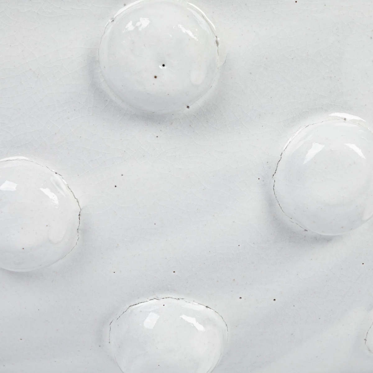 Close-up of white crackle glaze on a terracotta bowl with raised decorative dots.