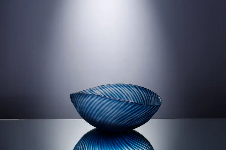 4.7 inch blue glass decorative bowl with a textured, wavy ribbed pattern on a reflective surface.