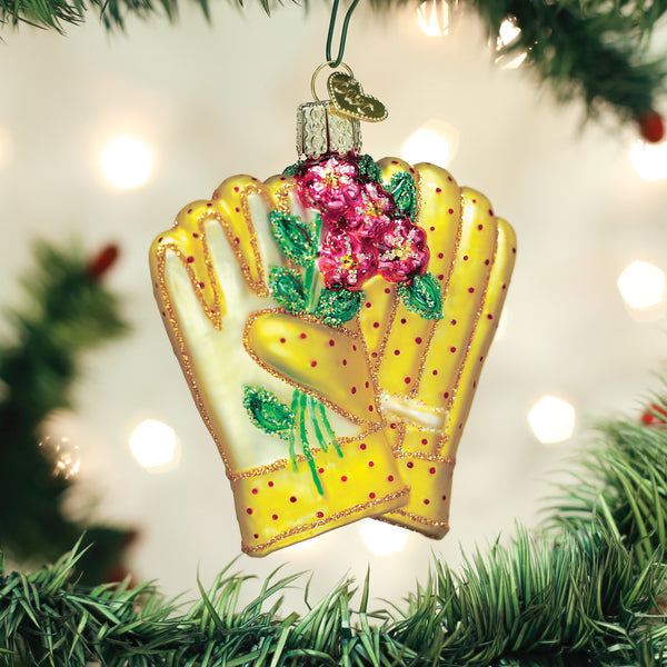 Yellow polka dot gardening gloves glass ornament with pink flowers and green glitter accents.