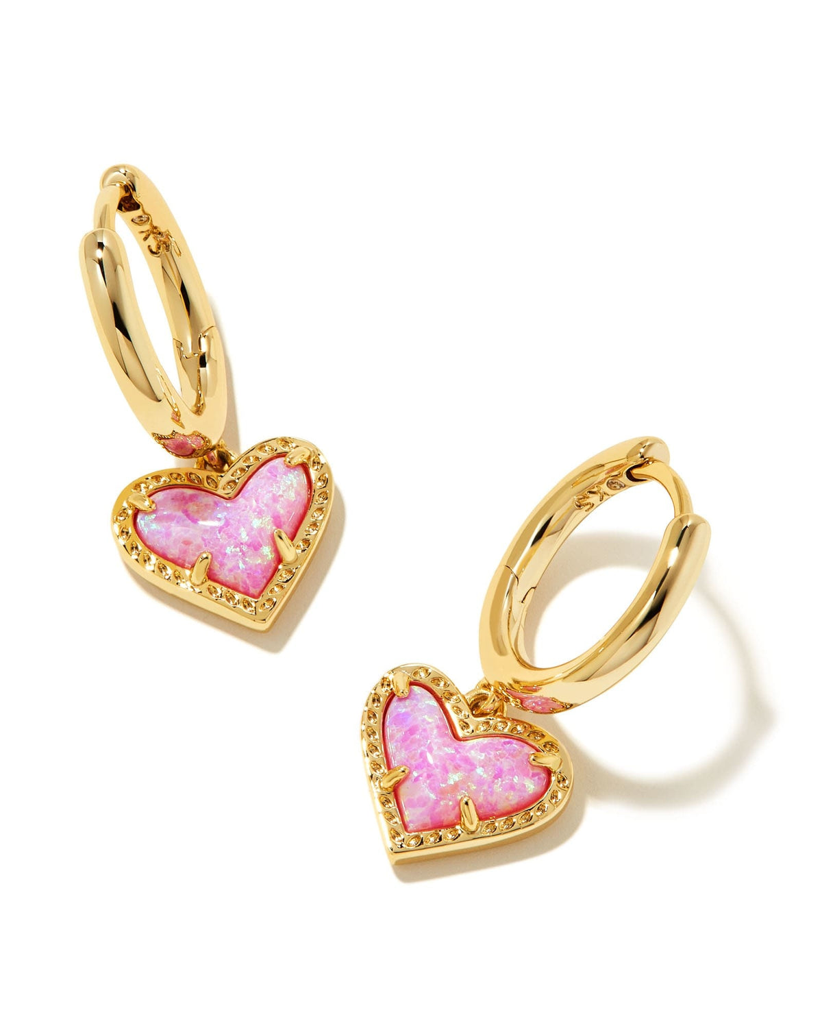 Gold huggie earrings featuring a heart charm with asymmetrical bubblegum pink and gold tones.