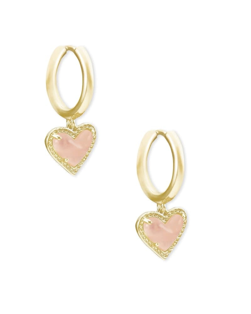 Gold huggie earrings featuring a heart charm with rose quartz accents in an asymmetrical hinge design.