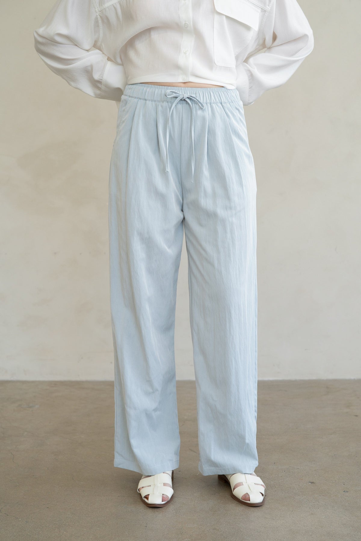 Aurora wide-leg pants in soft beige rayon with an elastic drawstring waist and side pockets.