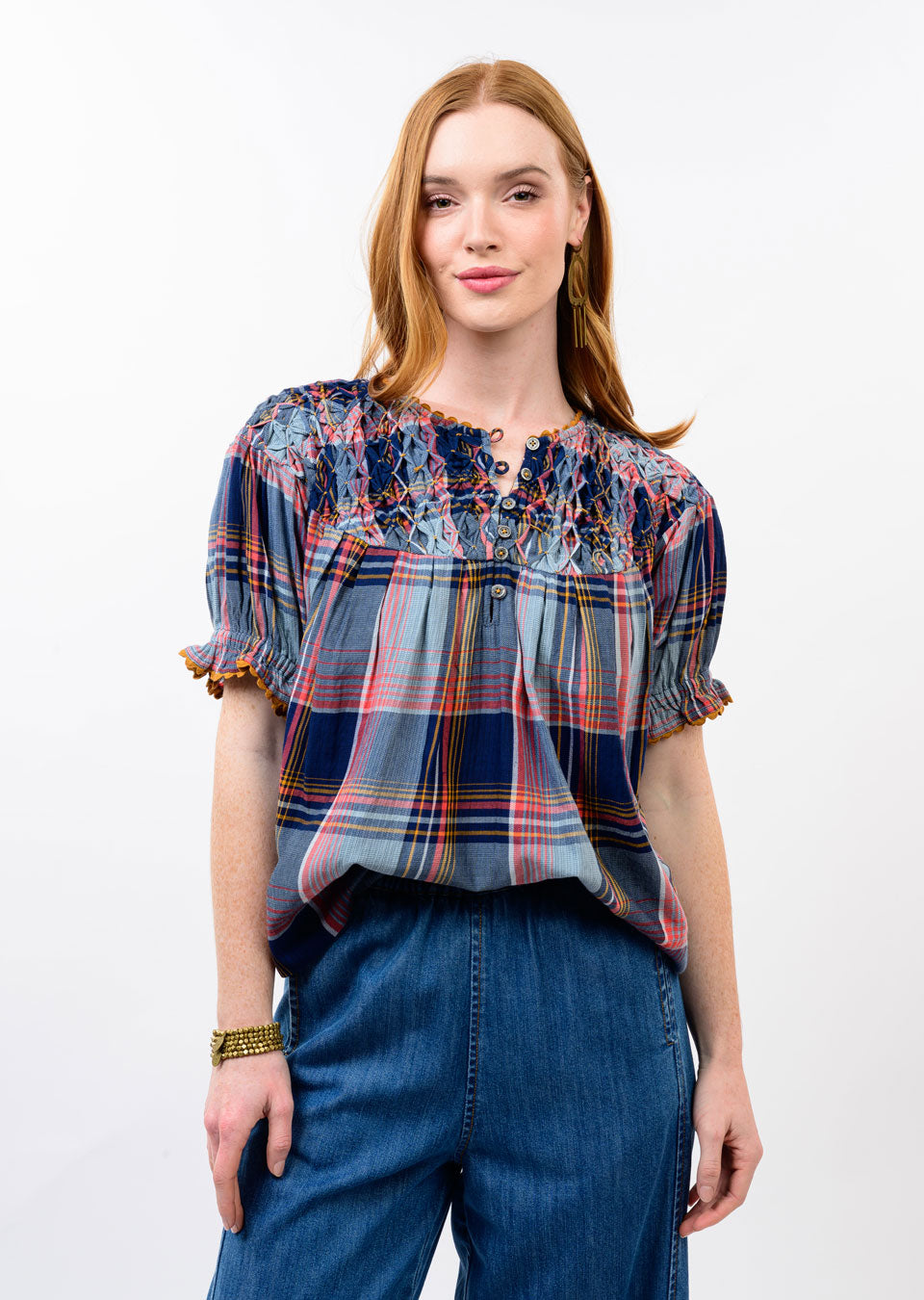Woman wearing the Cindy Smocked Neck Top in a blue and red plaid pattern with denim pants.