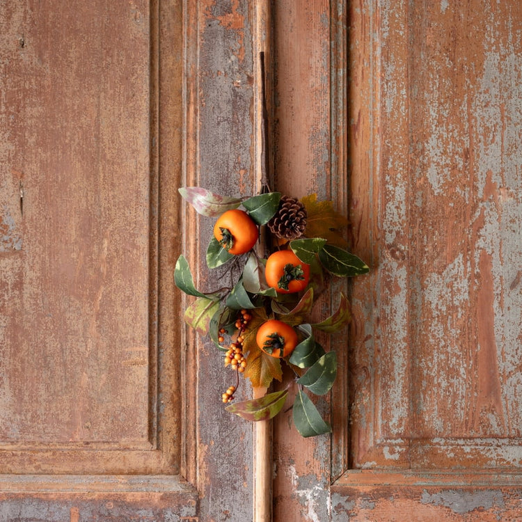Autumn Persimmon pick with an orange persimmon fruit on a green stem and brown branch.
